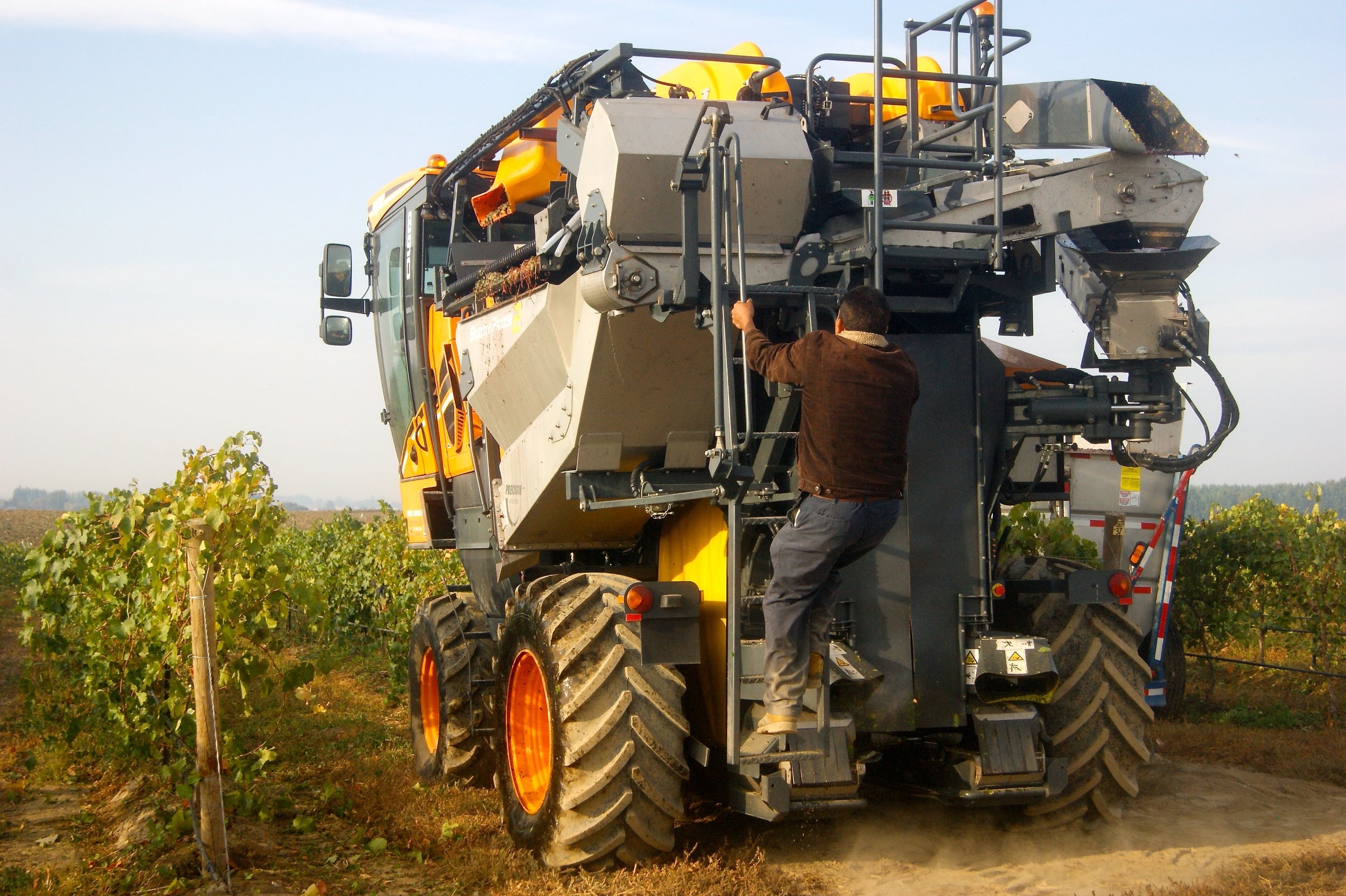 A technician working on a harvester in the vineyard